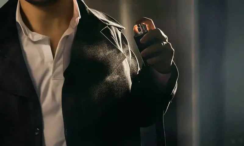 Man in formal wear spraying premium perfume on chest, luxury fragrance for men