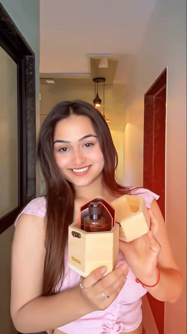 Woman holding a wooden box with a Inixio Perfume inside, smiling at the camera.